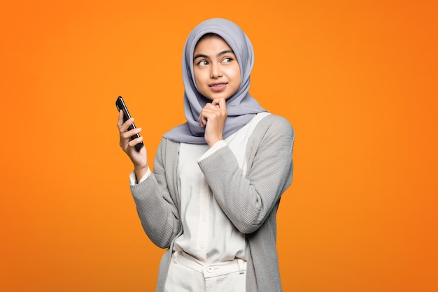 Beautiful Asian woman thinking and holding smartphone