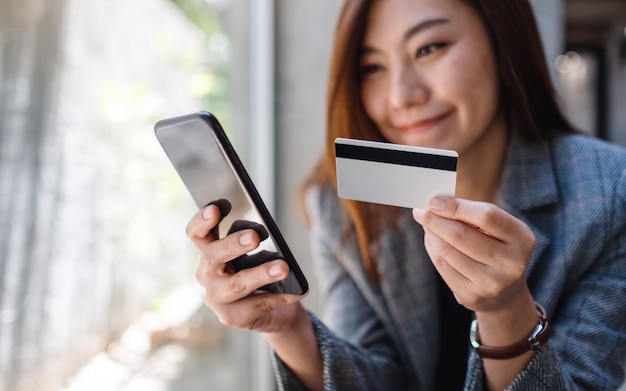 A beautiful asian woman using credit card for purchasing and shopping online on mobile phone