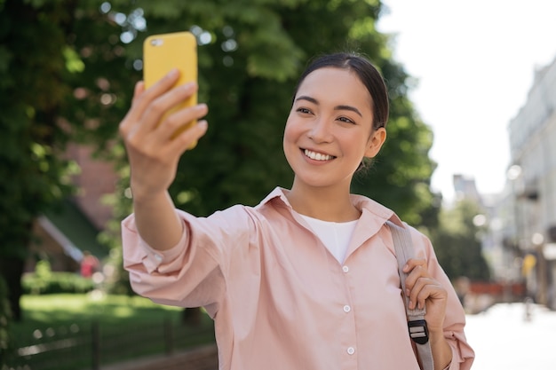 Beautiful asian woman using mobile phone taking selfie on the street