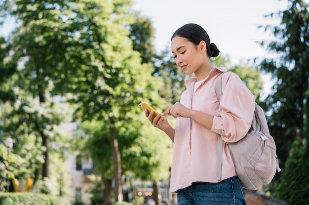 Beautiful asian woman using mobile phone, walking in park