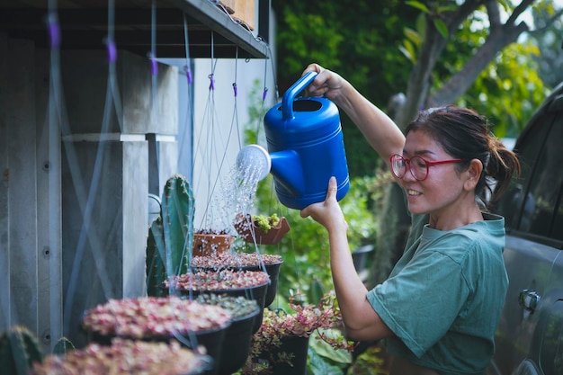 Beautiful asian woman watering colorful plant in hanging pot