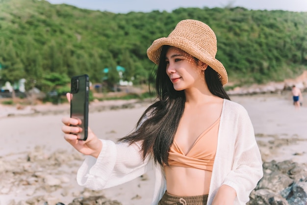 Beautiful asian woman wearing swimming suit make a selfie on the beach in summer on holiday