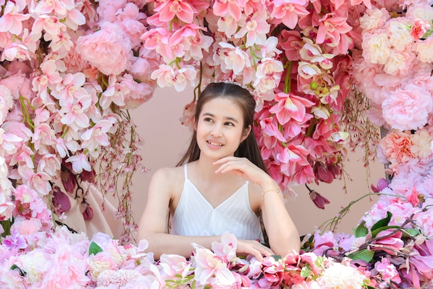 Beautiful asian woman wearing white dress sitting with beautiful pink flower .