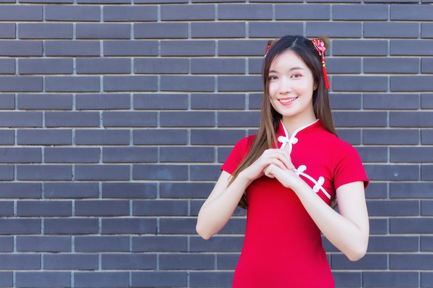 Beautiful Asian woman with long hair who wears a red Cheongsam dress in Chinese new year theme.