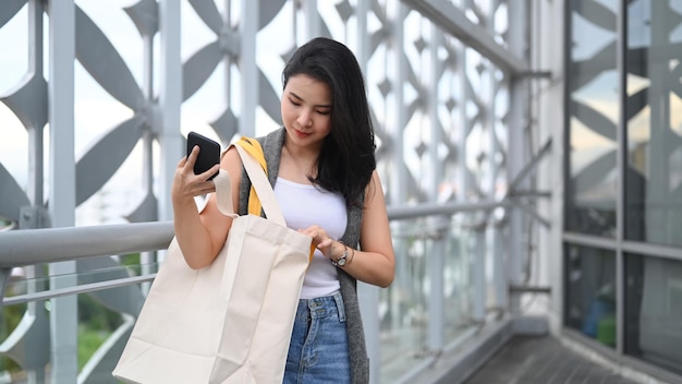 Beautiful asian woman with shopping bags walking on terrace of shopping mall in the evening