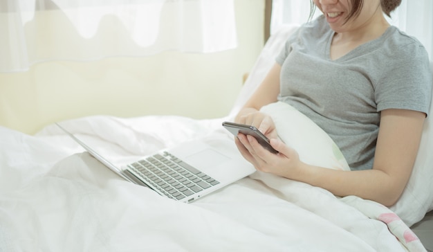 Beautiful asian women working at home and team conferencing using notebook and smartphone