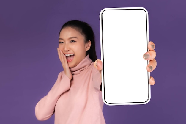 Beautiful Asian young woman Excited surprised girl showing big smart phone with blank screen white screen isolated on purple background Display Mock Up Image