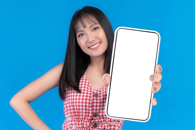 Beautiful Asian young woman Excited surprised girl showing big smart phone with blank screen white screen for Mobile App Advertising isolated on blue background smart phone display Mock Up Image