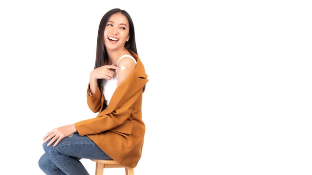 Beautiful Asian young woman smile and showing her arm after getting the covid19 vaccine dose antivirus vaccination