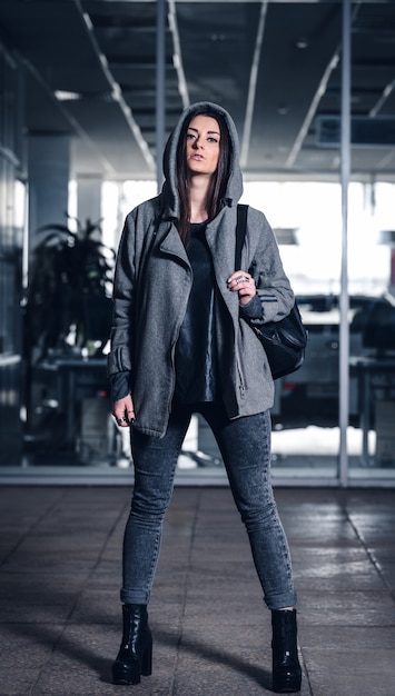 Beautiful athletic girl with dark hair and hoddie on and a backpack on the gym