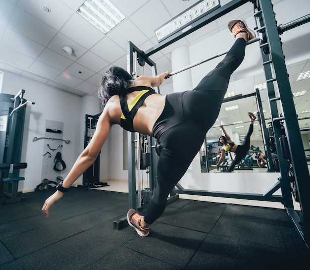 Beautiful athletic young woman making exercise at the gym. Young woman with muscular body.