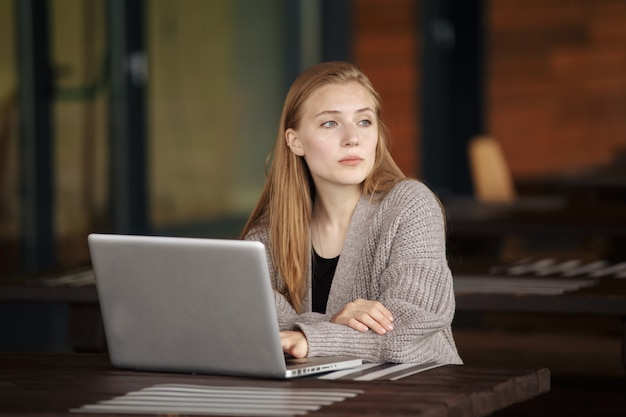 Beautiful attractive girl working in a coffe shop with a laptop