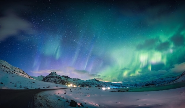 Beautiful Aurora borealis Northern lights glowing over snow mountain and coastline in the night sky at Lofoten Islands