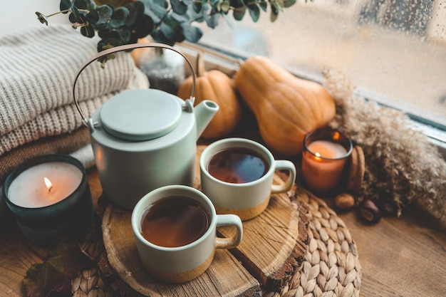 Beautiful autumn composition with burning candles and cup of tea on window sill