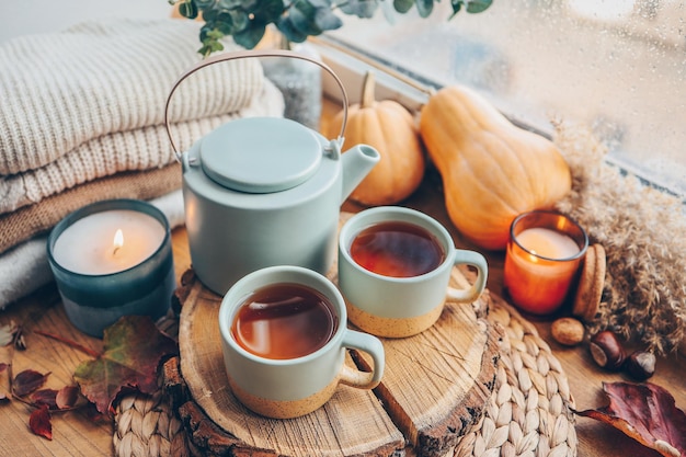 Beautiful autumn composition with burning candles and cup of tea on window sill