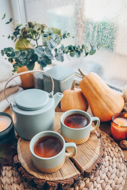 Beautiful autumn composition with burning candles and cup of tea on window sill