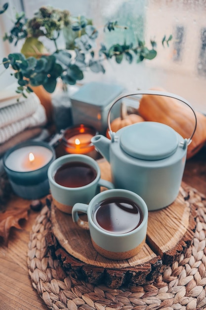 Beautiful autumn composition with burning candles and cup of tea on window sill