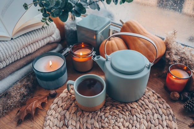 Beautiful autumn composition with burning candles and cup of tea on window sill