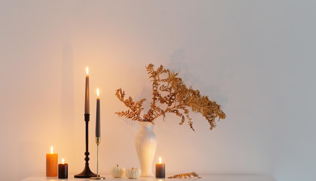 Beautiful autumn home decor with burning candles in white interior