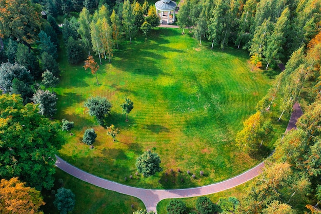 A beautiful autumn park with yellow and orange trees wooden benches and paved paths