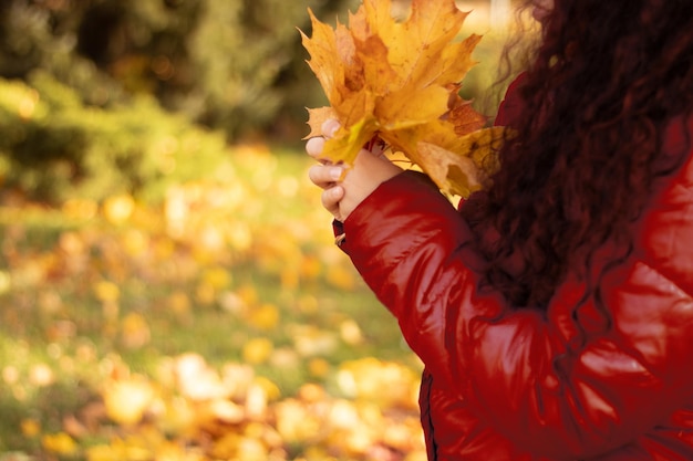 Beautiful autumn woman with autumn leaves on the background of autumn nature