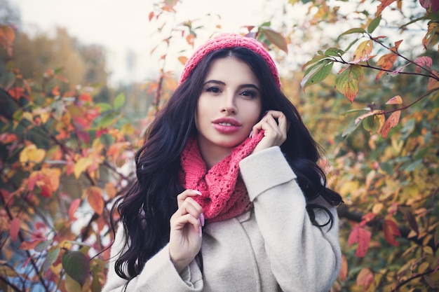 Beautiful autumn woman with long dark hair holding red maple leaf outdoors Beautiful girl in fall park