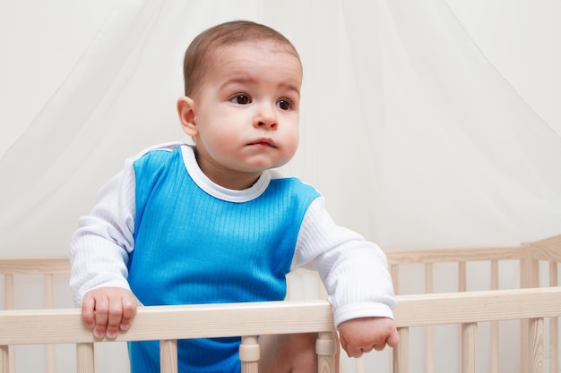 Beautiful baby in the bed on white background look at one side