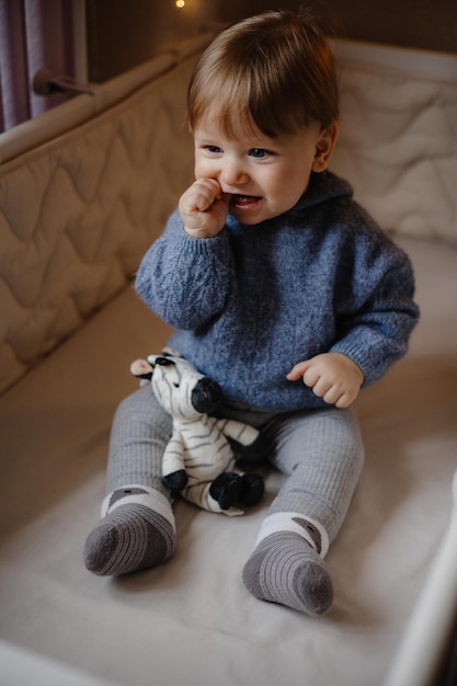 Beautiful baby is playing with him in the crib