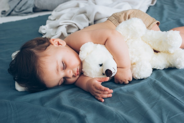 Beautiful baby sleeping with his teddy bear aside, family concept