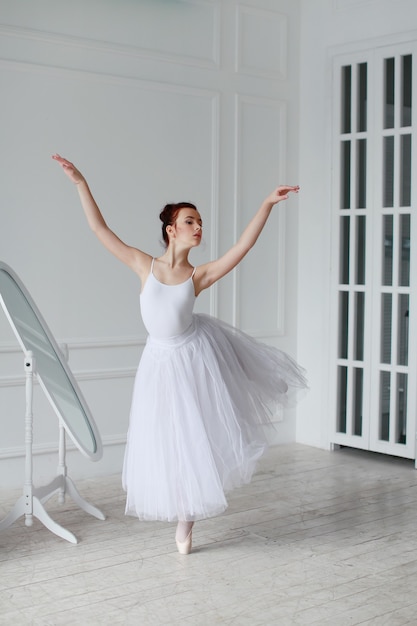 Beautiful ballet dancer in a white room