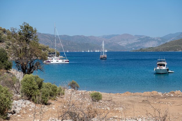 Beautiful bay lagoon beach with turquoise water with sailing boats and mountains