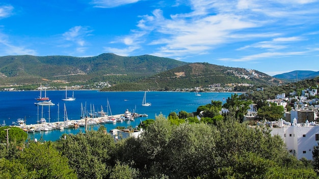 Beautiful bay with blue water and marina with boats Small town and green mountains