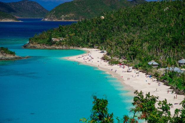 Beautiful beach with a lot of people and green hills foreground, St. John US Virgin Islands.