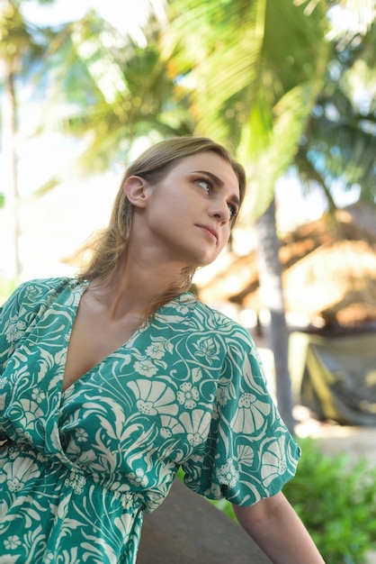 Beautiful Belarus woman posing  in green dress against palms in tropics