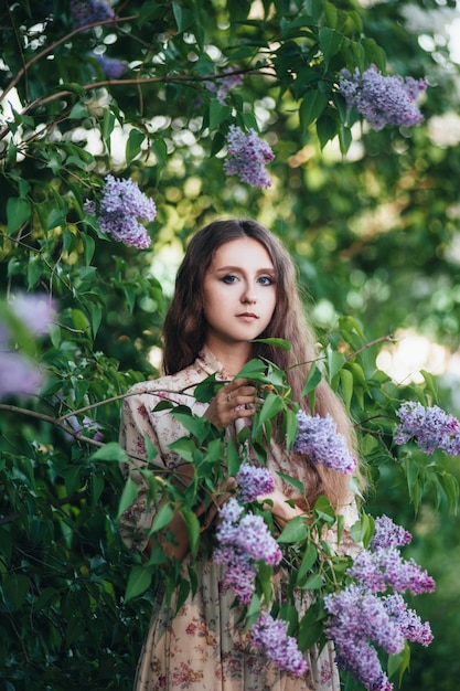 Beautiful big-eyed girl near the lilac tree. 