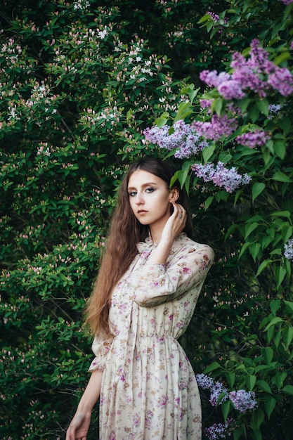 Beautiful big-eyed girl near the lilac tree. 