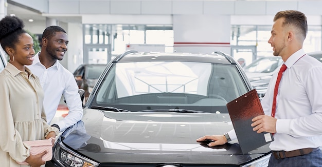 Beautiful black afro couple attentively listen to consultant in dealership