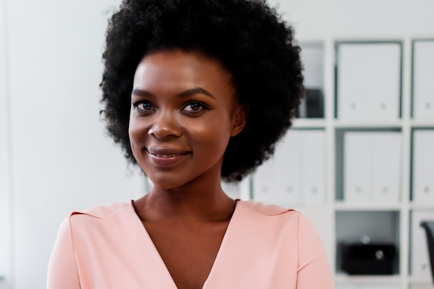 Beautiful black woman in pink dress in the background office shelves with binders