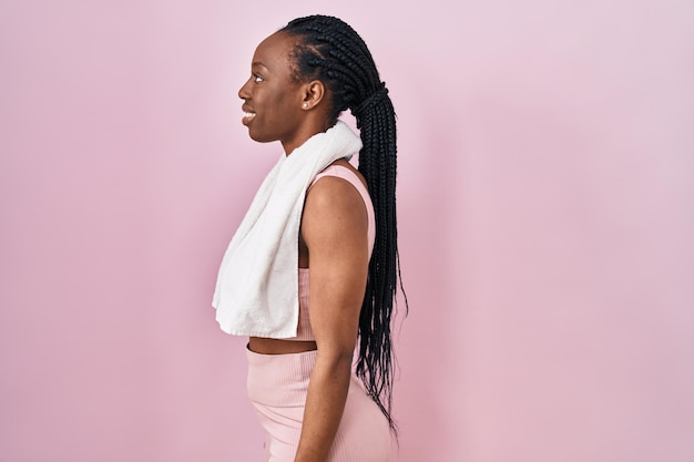 Beautiful black woman wearing sportswear and towel over pink background looking to side relax profile pose with natural face with confident smile