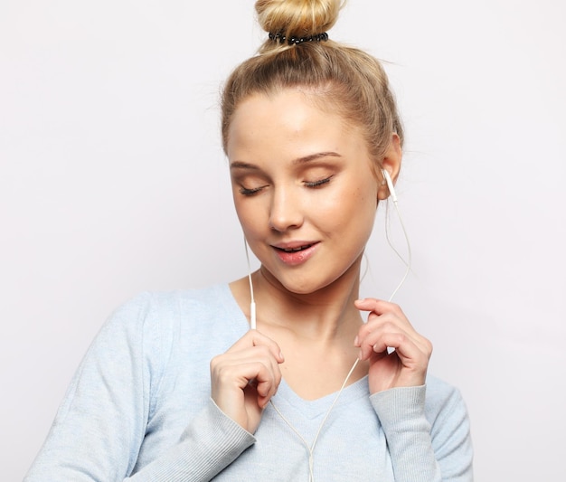 Beautiful blond woman in headphones listening to music on white background