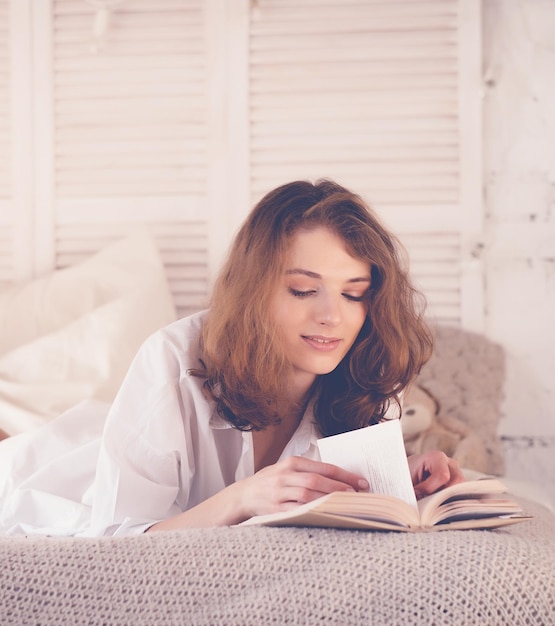 Beautiful blond woman reading book in the bed Relaxing concept