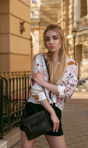 Beautiful blonde in black mini skirt posing on the street