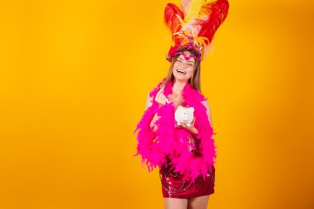 Beautiful blonde brazilian woman with queen clothes from samba school carnival Feather crown holding piggy bank and coin