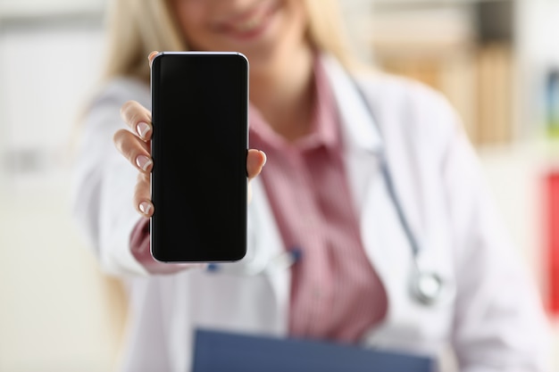 Beautiful blonde female doctor holding smartphone