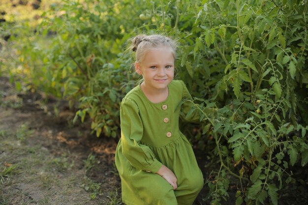 a beautiful blonde girl in a green dress and yellow boots is standing in the garden