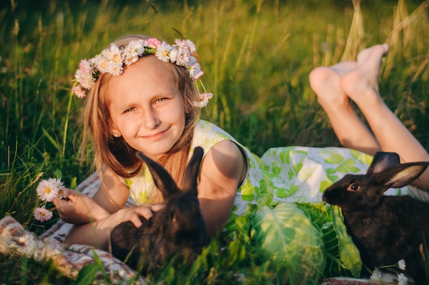 beautiful blonde girl lying on the grass with rabbits.