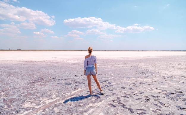 Beautiful blonde girl on a pink salty lake in summer