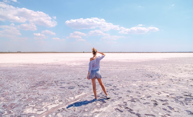 Beautiful blonde girl on a pink salty lake in summer