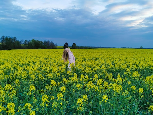 Beautiful blonde girl in a rape field before the storm Girl and flowers