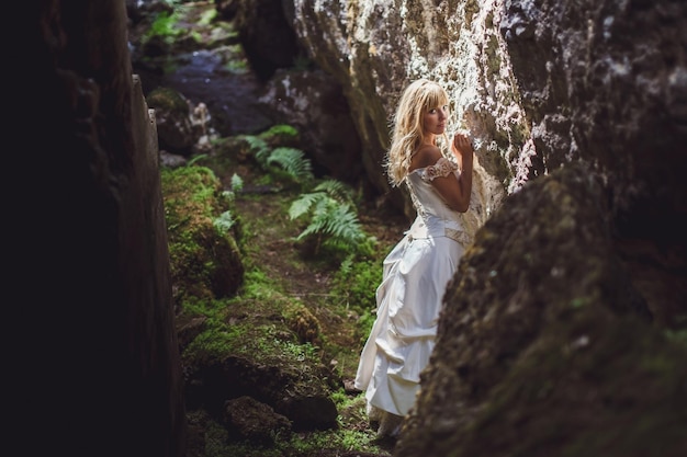 Beautiful blonde girl in a white dress with a corset in a deep dark cave